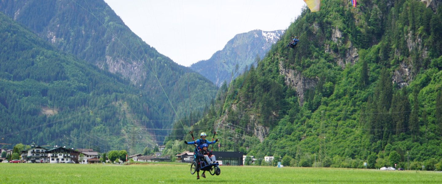 Bild einer alpinen Landschaf, Häuser stehen im Grünen vor einer Bergkette